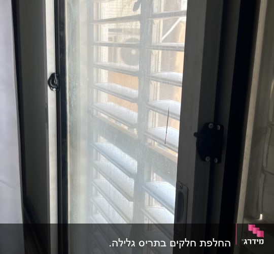 תריסים על חלון עם אור שמש חודר